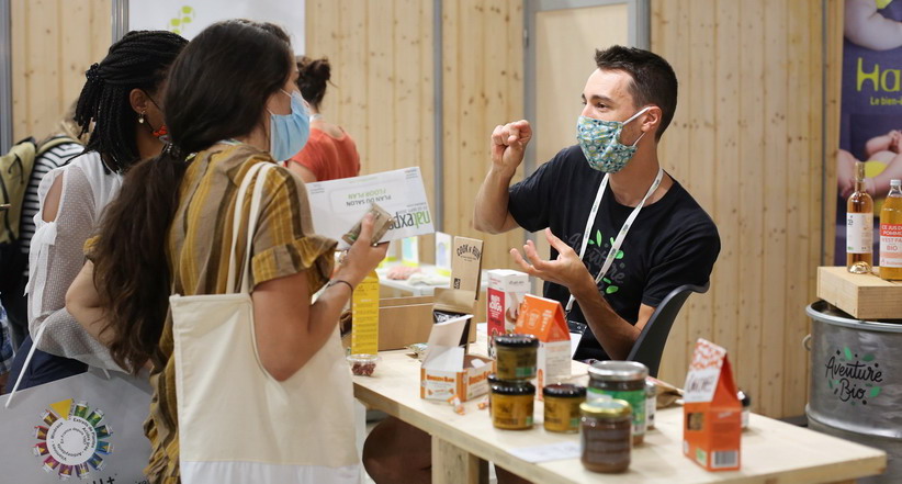 Discussion entre un exposant et des visiteurs au salon Natexpo.